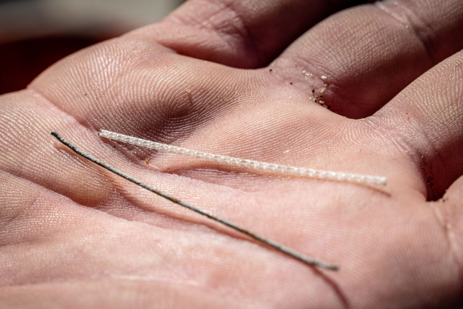Photo of a thin fibers of steel and polypropylene in the palm of a hand.
