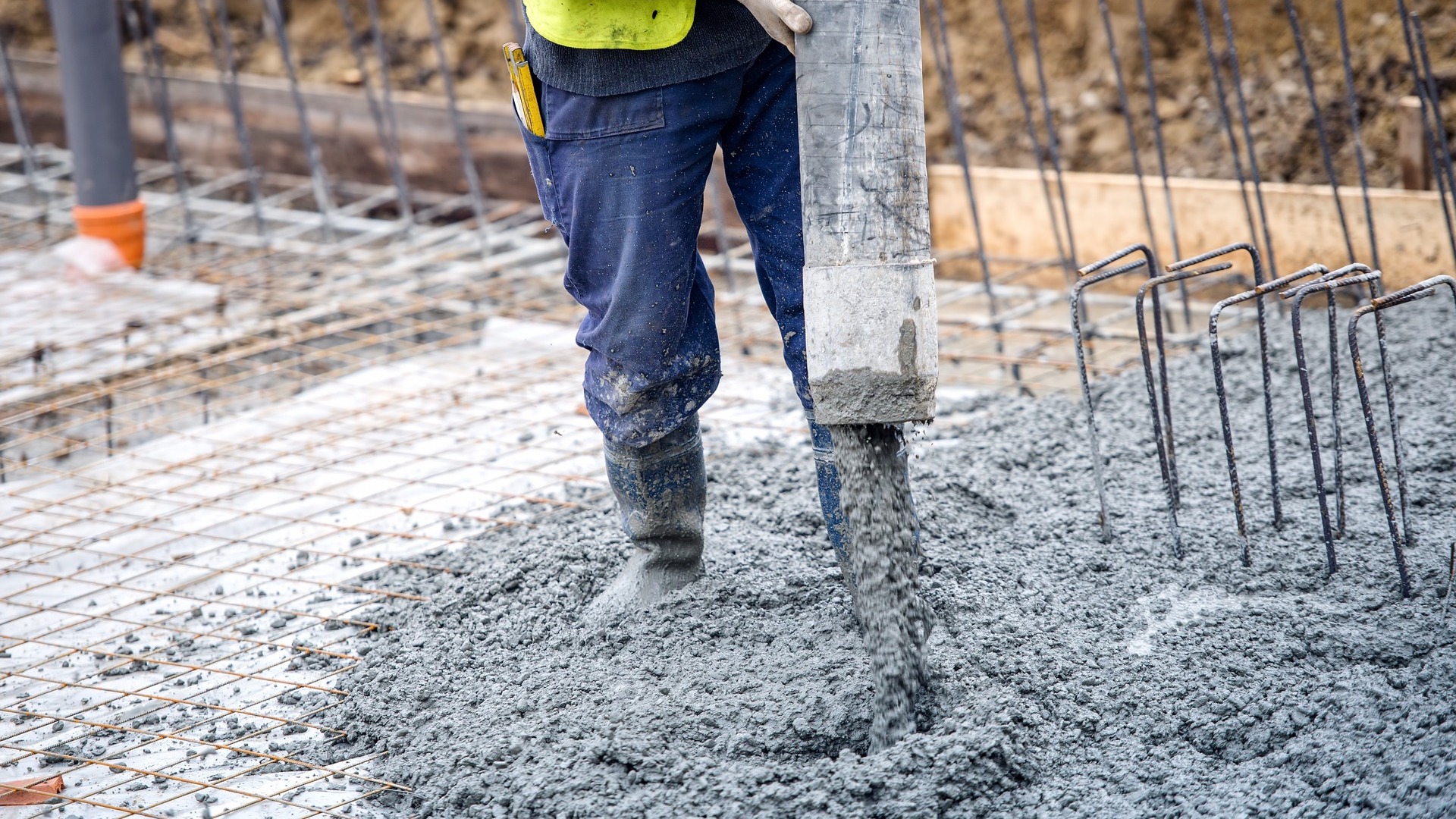 Stock photo of a worker pouring concrete from a mixing truck over a bed of rebar steel.