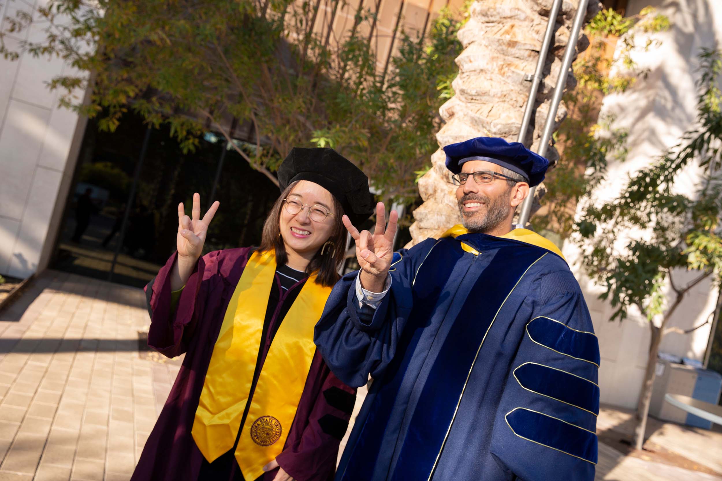 An ASU professor stands with his PhD student outside of the ASU Engineering PhD Hooding Ceremony