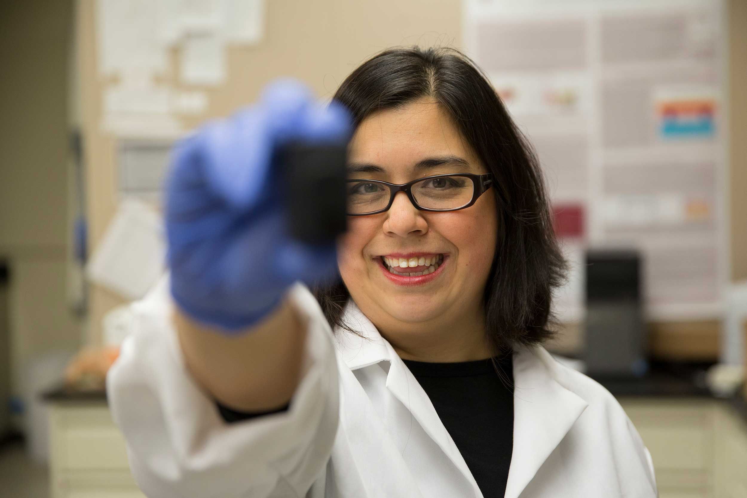 Professor Blain Christen holding up an object direct to the camera, smiling.